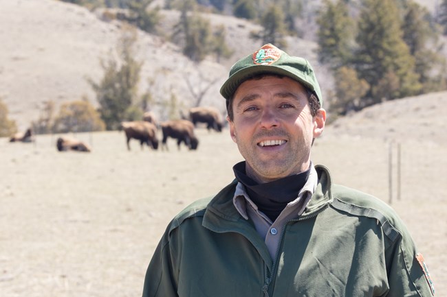 Chris Geremia standing with bison in the distance