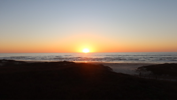 An orange sunrise covering the horizon over the ocean.