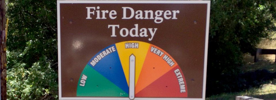 A sign with a half circle divided like a pie showing colors and words denoting fire danger.