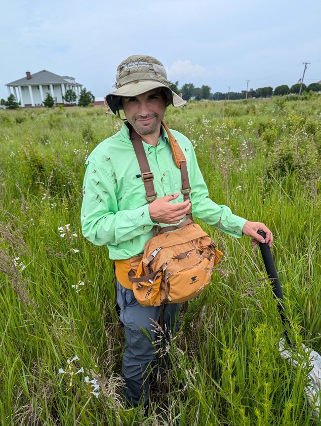 A person covered by mayflies standing in a field.