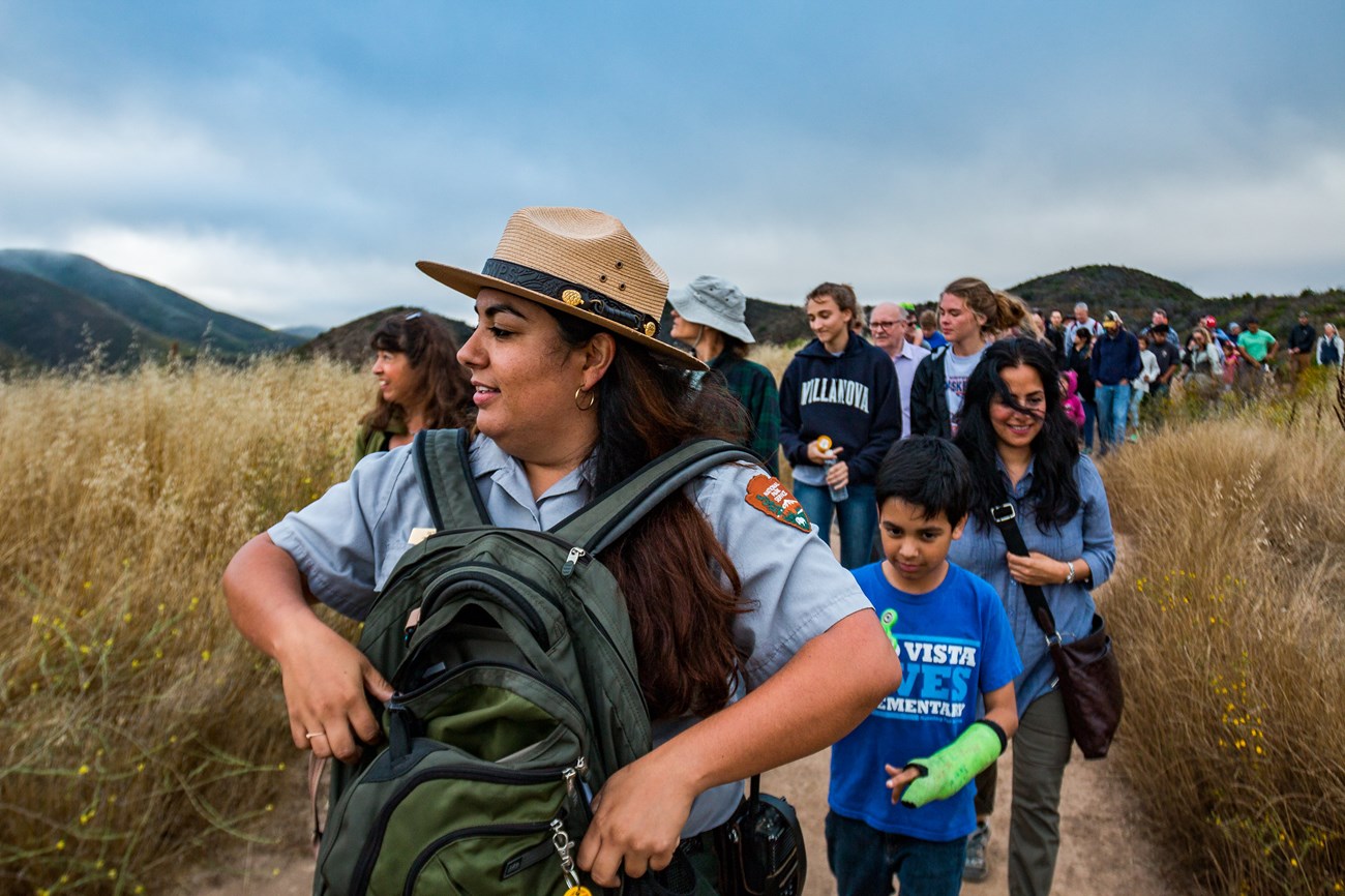 Ranger leading a large group through a dry grassland trail