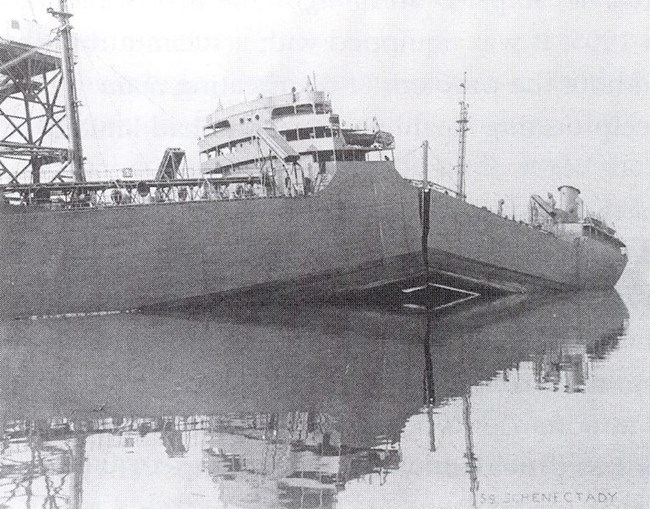 A large ship broken in two at dock.