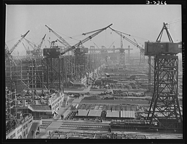 Multiple drydocks with heavy scaffold and dozens of industrial cranes.