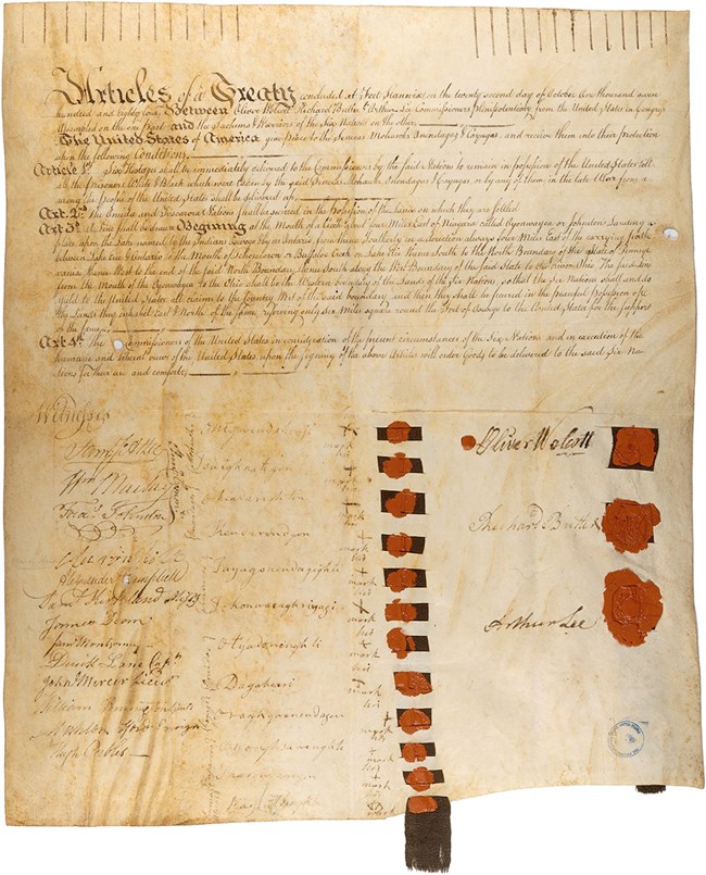 A yellowed parchment document with red marks. You can see fine handwriting on it. It is beginning to fade.