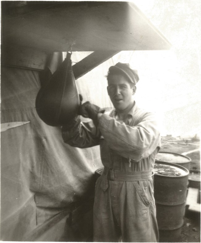 Black and white photo of young man punching a small punching bag.
