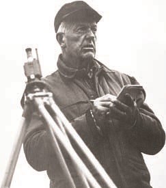 Glaciologist William O. Field holds pencil and notepad next to surveying tripod. Black and white image.