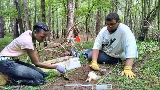 Two people doing archaeology in a forest