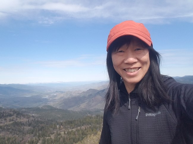 Biologist flashes a smile in front of a scenic vista.