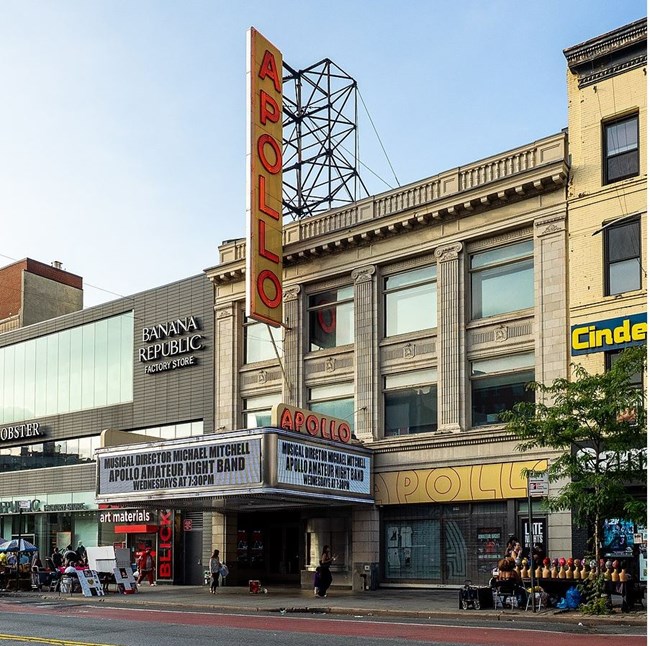 building attached to a main street corrido with a large luminescent sign across the entrance and a tall sign with the name of the theater in lights.
