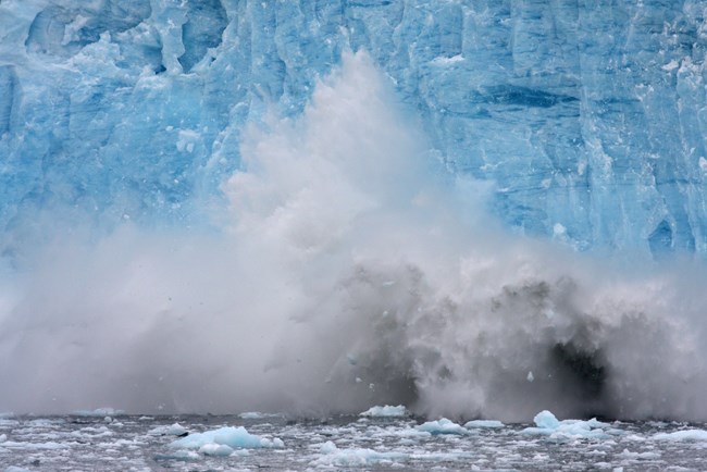 Chunks of ice fall into the ocean off the front of a glacier.