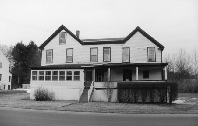 two-story, wood-framed rectangular house with a porch