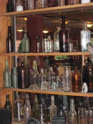 Several shelves of old bottles of various colors.