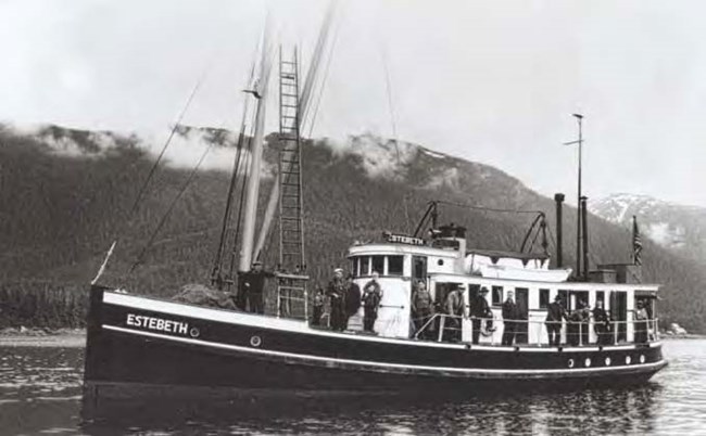Black and white image of a boat named "Estebeth" with people standing on the deck