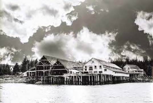 Black and white photo of large buildings on a wharf