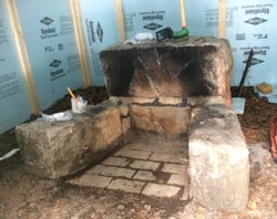 a stone firepit surrounded by blue temporary walls and tools