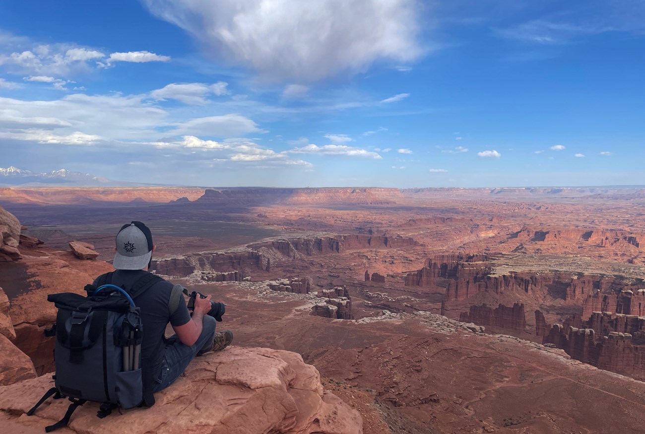 Photo of a seated person looking over a vast expanse of canyon country