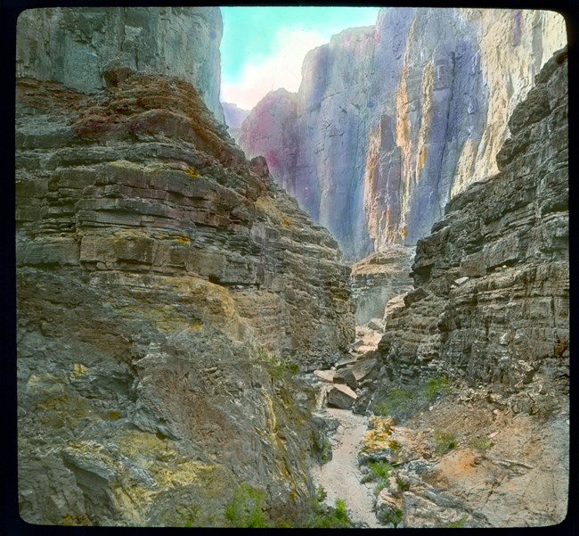 Two beige rock walls with a larger cliff in the background.