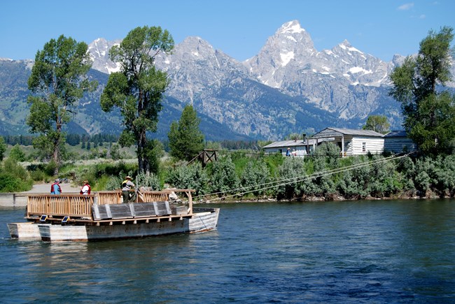 Park visitors ride a replica of Menor's Ferry along the Snake River in Grand Teton NP