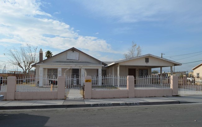 single story house with a brick and metal fence and low hanging eave over front entrance