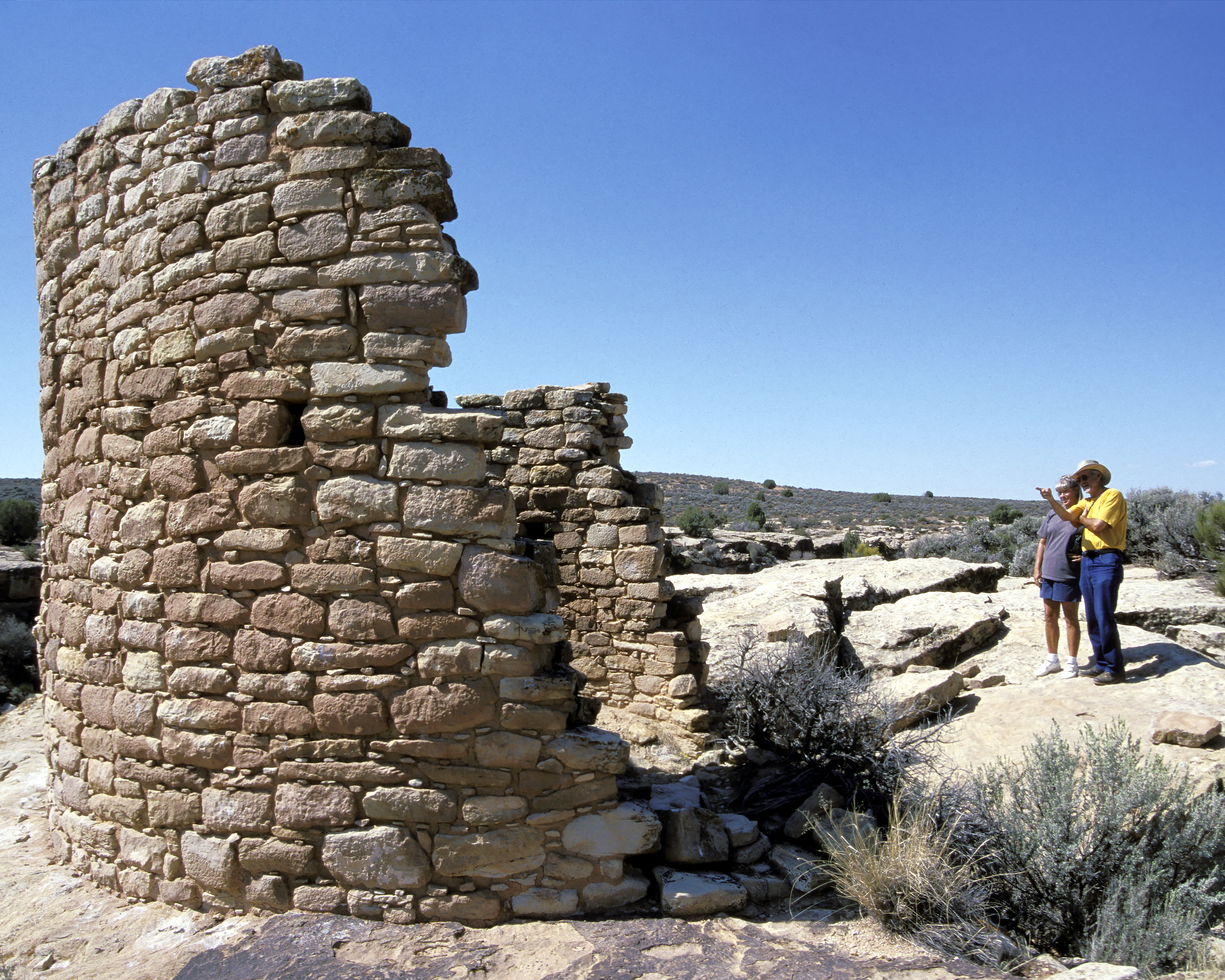 two people look at a round tower constructed of stones