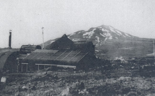 Black and white photo of military buildings in front of a volcano
