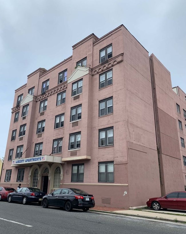 The Liberty Hotel is a five-story, U-shaped, brick building that is seven bays at the first story and six bays at the upper stories. The main entrance is recessed in the center of the first story under a metal and wood canopy with a metal sign