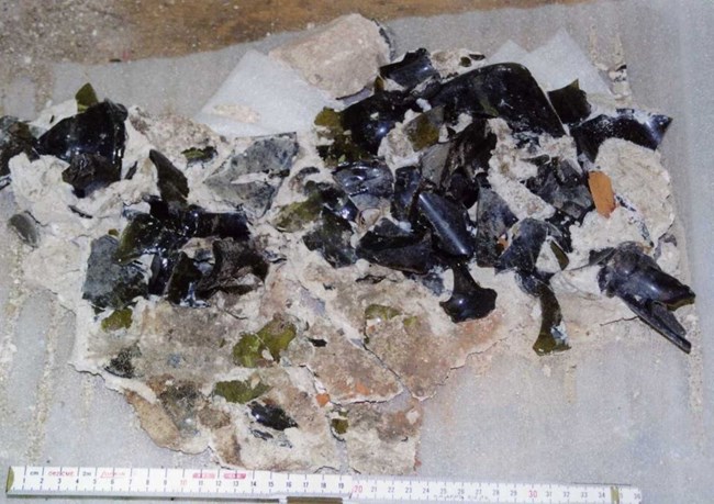 broken bottles of dark brown and green glass held together with white substance