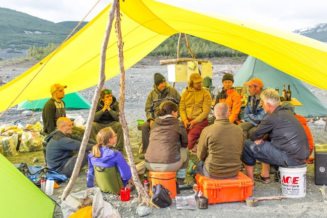 Researchers sitting in circle under tarp