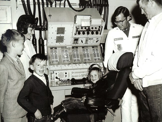 A family poses in front of a missile combat console in an underground control center