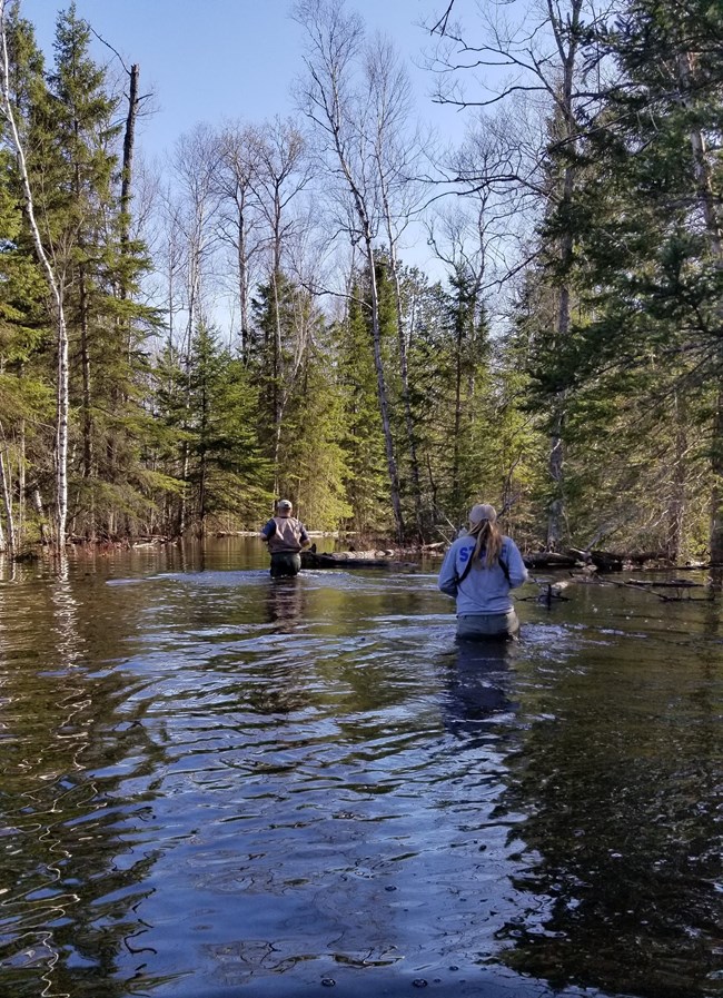Two people crossing body of water.