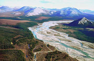 The Agashashok River runs through the mountainous region of Noatak National Preserve on a sunny day.