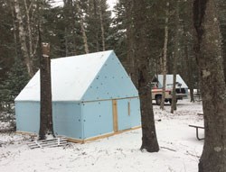 blue tent in snowy campground with vehicle in background