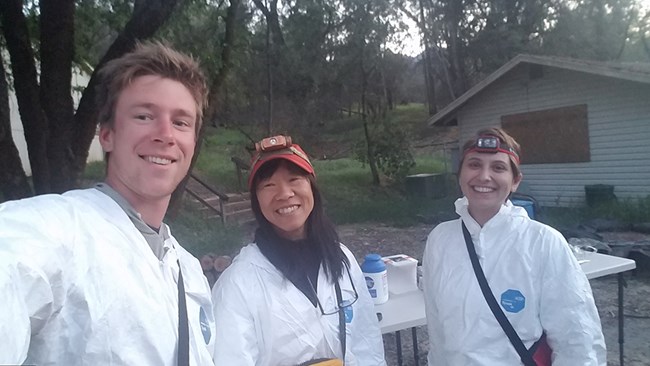 Biologists wearing protective gear smile at the camera.