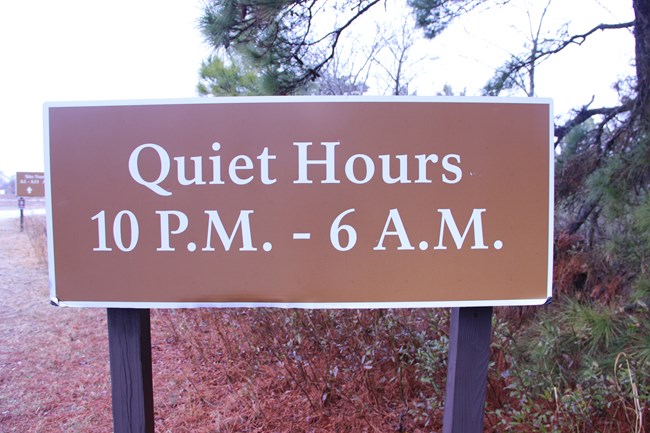 A brown sign listing quiet hours of: 10pm - 6am