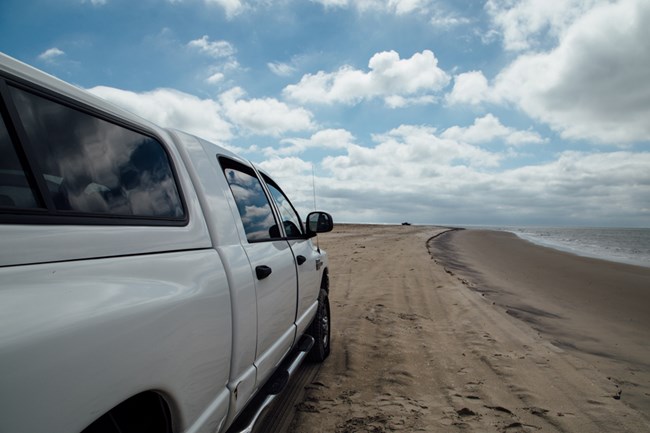 view of Oversand Vehicle Zone, truck, beach and ocean. Links to OVersand Vehicle Zone video.