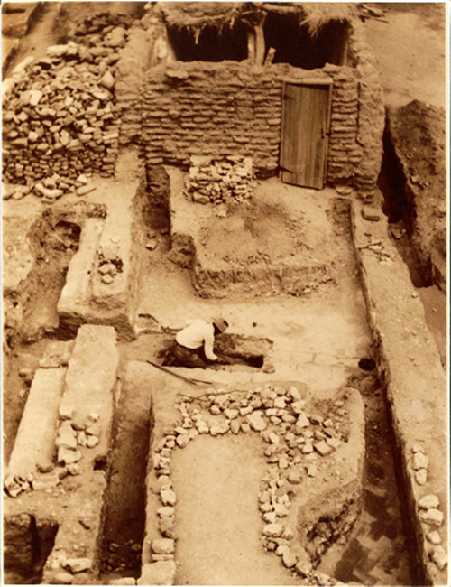 A person kneeling down to excavate an archeological site.  Tumacácori National Historical Park, 1935