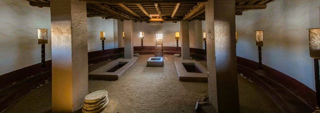 The interior of the Aztec West Great Kiva showing columns, floor vaults, a fire pit, and windows to outer rooms.