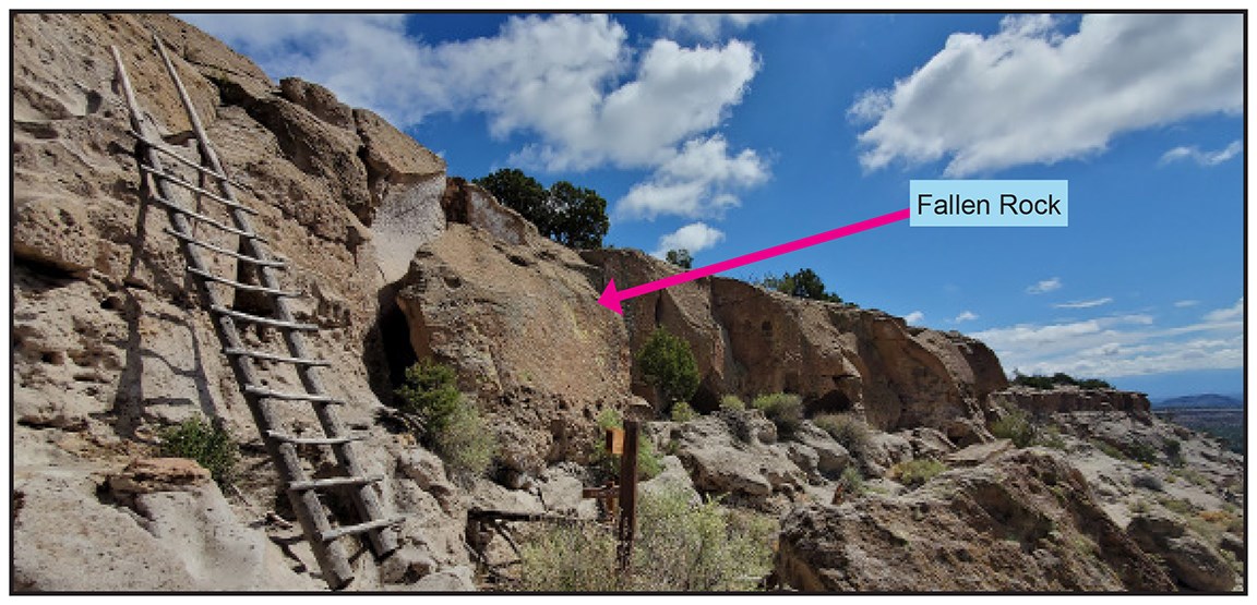 a cliff face with a wooden ladder and an arrow pointing at a fallen rock