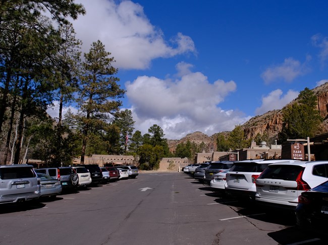 Many cars of different makes, models, and colors parked in a parking lot.