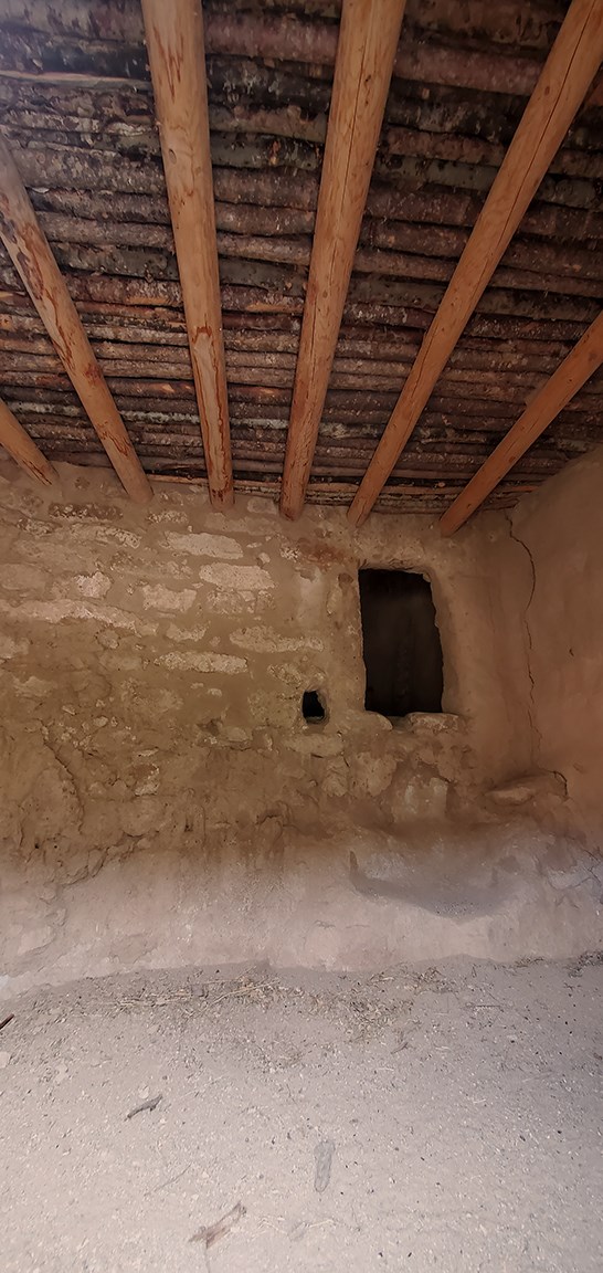 inside of a stone room with wooden beams in the ceiling