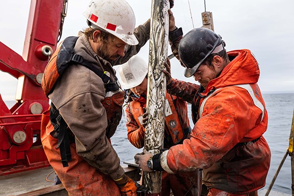 Two men, and one woman, position a tube for coring.