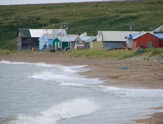 Houses and vehicles sit near the shoreline in the community of Deering, Alaska.