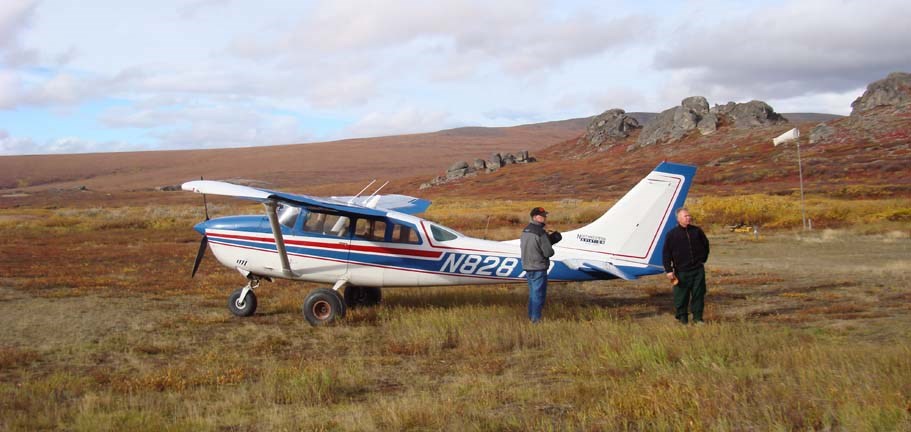Two men with a small airplane near Serpentine Hot Springs in the fall