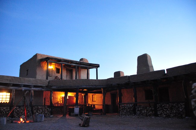 Adobe fortress with lanterns and lighted windows near sunset