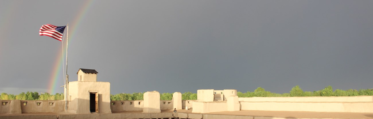 A rainbow appears in the dark skies to the east of the fort.