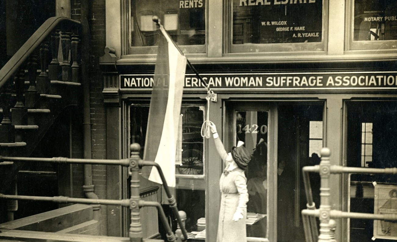 Woman reaches up to position a flag in front of basement office