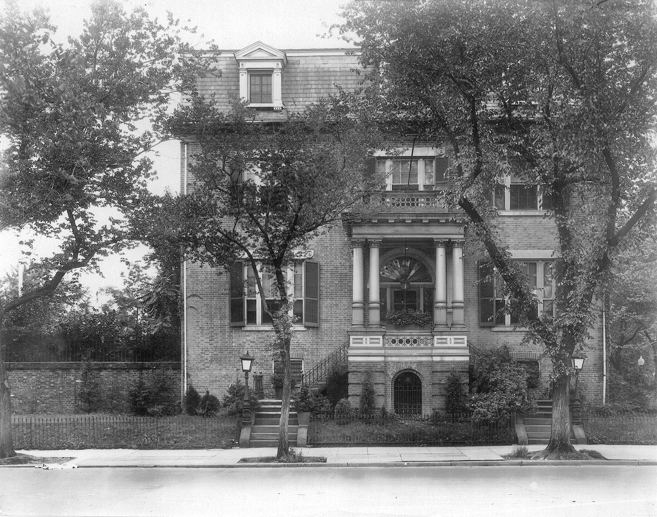 Three story brick federal style house with mansard roof and front portico