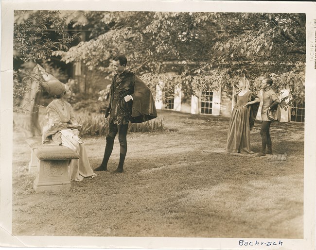 Two couples in Shakespearean costume pose outside the Belmont House in the backyard