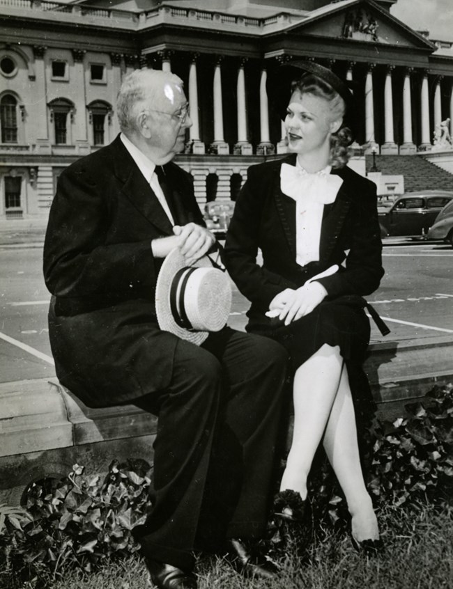 Man and woman seated outside with US Capitol Dome in background