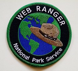 A circular patch that says "Web Ranger National Park Service" around the outside of a globe. The globe has a ranger hat in front of it.